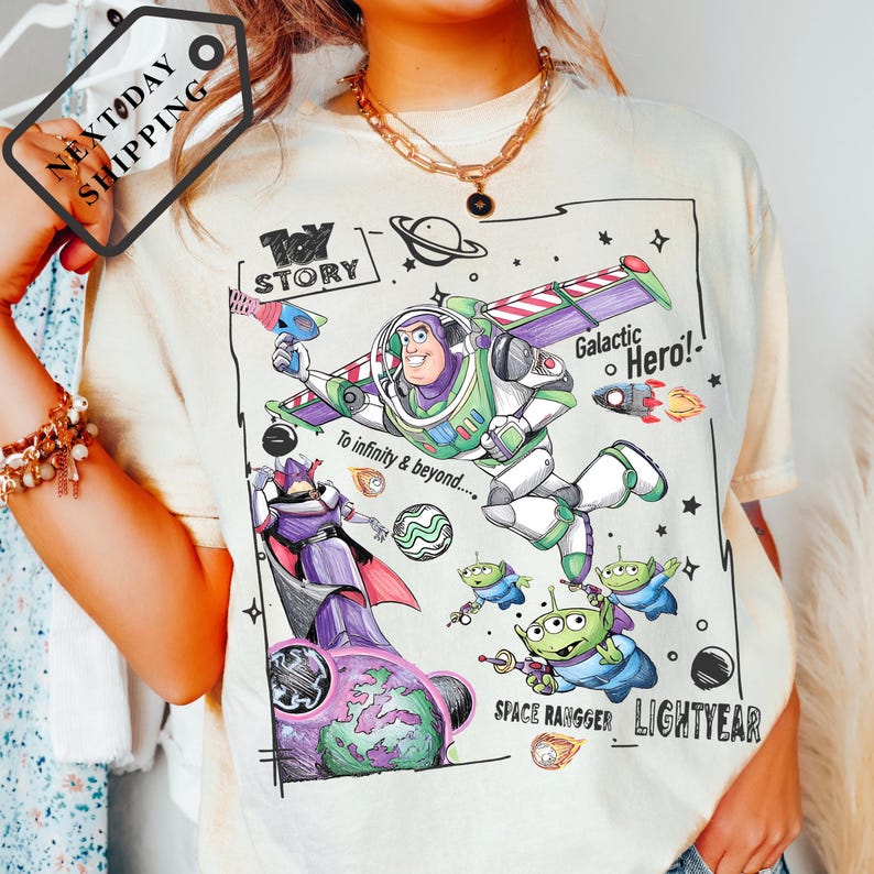 A person wearing a white t-shirt with a colorful graphic design featuring characters from the Toy Story franchise, including Buzz Lightyear and a space ranger.