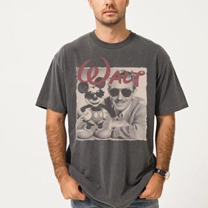 A man wearing a gray t-shirt with a graphic design featuring a man and a character from Disney.