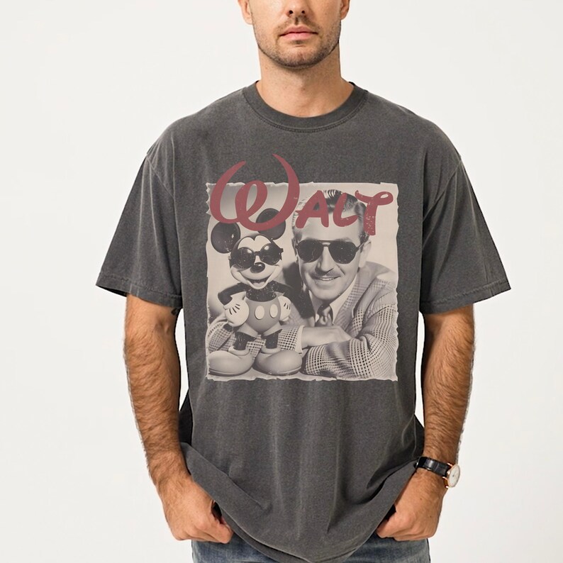 A man wearing a gray t-shirt with a graphic design featuring a man and a character from Disney.