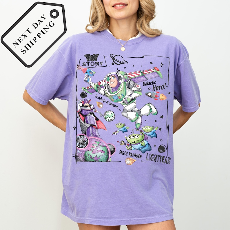 A woman wearing a purple t-shirt with a colorful graphic design featuring characters from the Toy Story movie, including Buzz Lightyear and a space ranger.