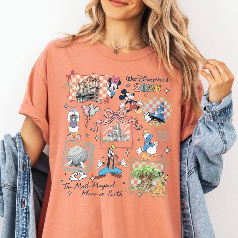 A woman wearing a t-shirt with a Disney World-themed design, including various Disney characters and landmarks.