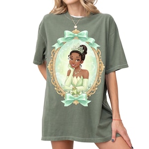 A woman wearing a green t-shirt with a graphic of a princess in a green dress and crown.