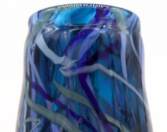 May include: A blue glass vase with white, purple, and green swirls throughout. The vase has a rounded bottom and a wide opening.