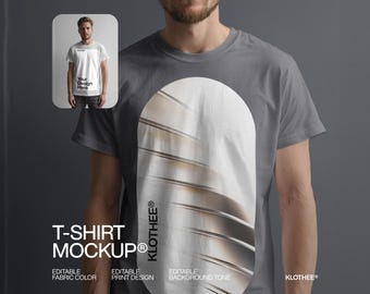 May include: A grey t-shirt mockup with a white oval design and the text "KLOTHEE®". The image includes a smaller inset showing a person wearing a white t-shirt with the text "Your Design Here". The words "T-SHIRT MOCKUP®" are also visible.
