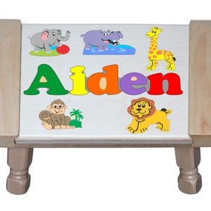 May include: A wooden step stool with a colorful animal puzzle on top. The puzzle features a monkey, lion, giraffe, elephant, and hippopotamus. The name "Aiden" is spelled out in colorful letters.