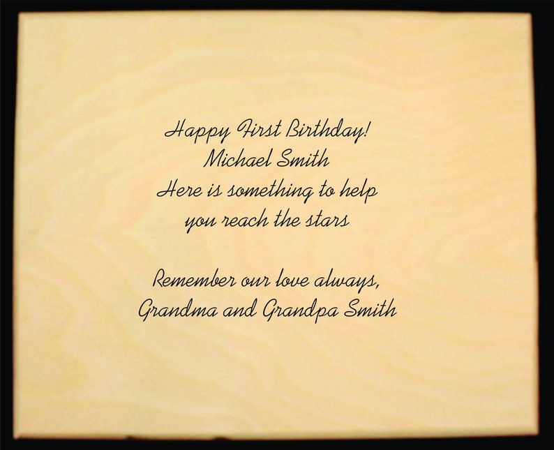 Puede incluir: Placa de madera de color claro con texto negro. El texto dice: "&iexcl;Feliz primer cumplea&ntilde;os! Michael Smith. Aqu&iacute; hay algo para ayudarte a alcanzar las estrellas. Recuerda siempre nuestro amor, abuela y abuelo Smith."