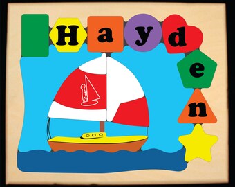Puede incluir: Un rompecabezas de madera con el nombre Hayden, deletreado con letras de colores en diferentes formas. El rompecabezas también incluye un velero con una vela roja y blanca, una estrella amarilla y otras formas geométricas.