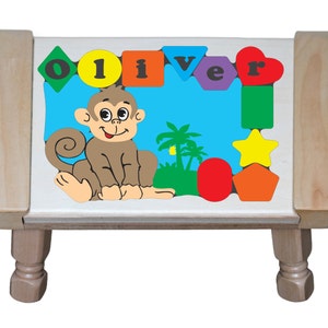 May include: A wooden stool with a colorful puzzle top featuring a monkey, palm trees, and the name "Oliver". The puzzle pieces are shaped like letters, stars, and geometric shapes.