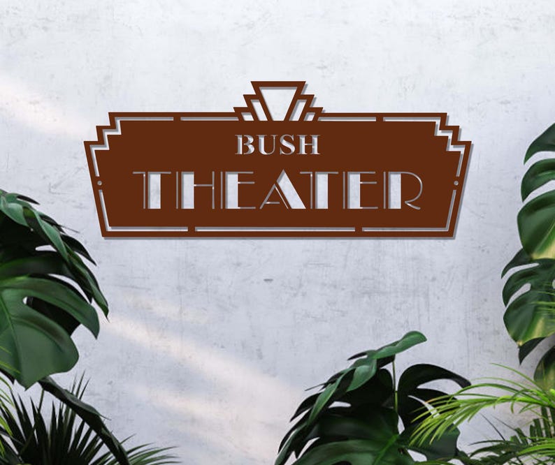 May include: A brown metal sign with a decorative art deco design. The sign reads "Bush Theater" in white lettering.