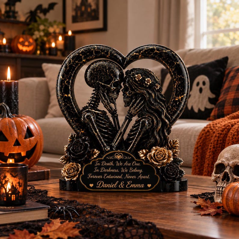 May include: A black and gold heart-shaped sculpture featuring two skeletons facing each other, adorned with roses. The base displays the text: In Death, We Are One. In Darkness, We Belong. Forever Entwined, Never Apart. Daniel & Emma.