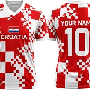 May include: A short-sleeved V-neck jersey featuring a red and white pixelated checkerboard pattern. The front displays the Croatian flag and the word CROATIA. The back shows the text YOUR NAME above the large white number 10 on a red background.