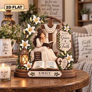 May include: A decorative tabletop figurine featuring a person reading a book, surrounded by white lilies, a cross, and a lantern. The base is inscribed with the name EMILY and the phrase WALKING BY FAITH, with additional text on books and signs.