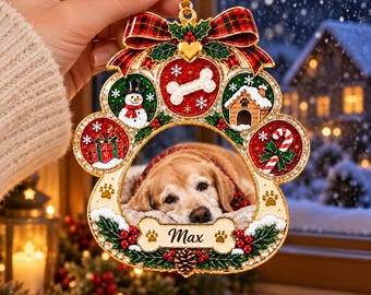 May include: A paw-shaped Christmas ornament featuring a central photo of a golden dog, a red plaid bow at the top, and festive icons including a snowman, dog house, gift, and candy cane. The bottom bone-shaped plaque displays the name Max.