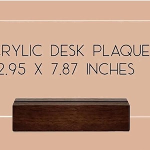 May include: A rectangular clear acrylic desk plaque with a dark brown wooden base. The plaque features the black text ACRYLIC DESK PLAQUE 2.95 X 7.87 INCHES printed on the surface. The item is displayed against a solid light tan background.