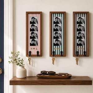 Puede incluir: Tres soportes de pared rectangulares de madera para llaves con fondos de rayas verticales en rosa, verde azulado y azul marino. Cada marco muestra una tira vertical de cuatro fotos en blanco y negro de una pareja, con iniciales doradas y un corazón.