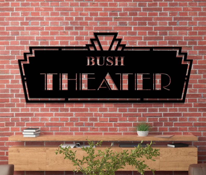 May include: Black metal sign with an art deco design. The sign reads "Bush Theater".