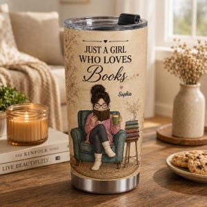 May include: A stainless steel tumbler with a beige background featuring an illustration of a person with glasses reading a book in a green armchair. The text reads "JUST A GIRL WHO LOVES Books" and "Sophia" with a small heart icon above the name.