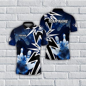 May include: A short-sleeved bowling shirt with a blue and white design. The shirt features a bowling ball and pins graphic, with the text "YOUR NAME" on the front and "TEAM NAME" on the back. The shirt has a black collar and button-up front.