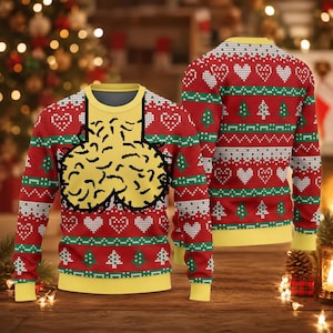 May include: A long-sleeve knit jumper featuring a red base with horizontal bands of green and white patterns, including hearts and Christmas trees. The front displays a large yellow graphic of two rounded shapes with black outlines.