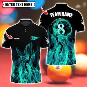 May include: Black polo shirt with a teal flame design and a pool ball graphic. The shirt features the text "YOUR NAME" and "TEAM NAME". The number 8 pool ball is on the back of the shirt. The text "ENTER TEXT HERE" is at the top.