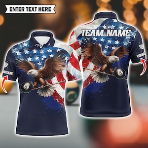 May include: Navy blue polo shirt featuring an American flag design with an eagle holding a pool cue and an 8-ball. The shirt has the text "TEAM NAME" on the back and "ENTER TEXT HERE" at the top.
