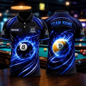 May include: A black polo shirt featuring a blue flame design with an 8-ball on the front and a 9-ball on the back. The front includes the text "YOUR NAME" and a billiard logo. The back features the text "TEAM NAME" and a billiard logo.