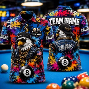 May include: A short-sleeved polo shirt featuring a vibrant paint splatter pattern in blue, orange, and yellow. The design includes a graphic of an eagle wearing sunglasses, a cap, and a gold chain, alongside an 8-ball and the text "YOUR NAME".