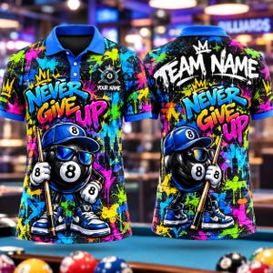 Puede incluir: Un polo de manga corta con un patrón de salpicaduras de pintura neón en azul, rosa, amarillo y verde. El diseño incluye un personaje de bola 8 de dibujos animados con gorra azul y gafas de sol, sosteniendo un taco de billar y el texto NEVER GIVE UP.