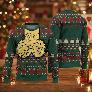 May include: A long-sleeve crew neck jumper in dark green featuring a repeating red and white geometric pattern of snowflakes and pine trees. The front displays a large, yellow, rounded graphic with black outlines and black hair-like details.