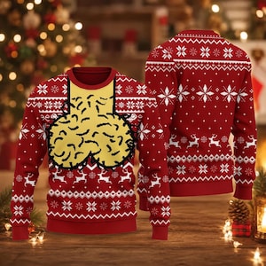 May include: A red long-sleeve jumper featuring a white and red Nordic-style pattern with reindeer and snowflakes. The front displays a large yellow graphic of two rounded shapes with black outlines, positioned below a yellow rectangular neck panel.