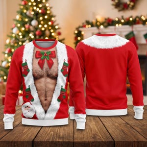 May include: A red long-sleeve sweatshirt featuring a printed graphic of a bare chest with body hair, framed by white faux fur trim. The design includes a red bow with holly, four small green and red stockings, and a Santa Claus face at the hem.