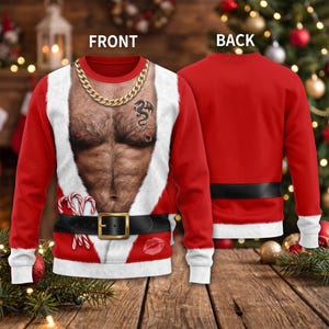 Könnte beinhalten: Ein rotes Langarm-Sweatshirt mit einem Aufdruck eines muskulösen, behaarten Oberkörpers, einer goldenen Kette, einem Drachentattoo und einem Brustwarzenpiercing. Das Design zeigt zudem einen weißen Kunstfellbesatz, einen schwarzen Gürtel und Zuckerstangen.