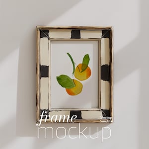 May include: A white frame with black checkered trim, featuring a watercolor painting of two yellow peaches with green leaves. The frame has the text "frame mockup" and "Mockup Sunday" written below it.