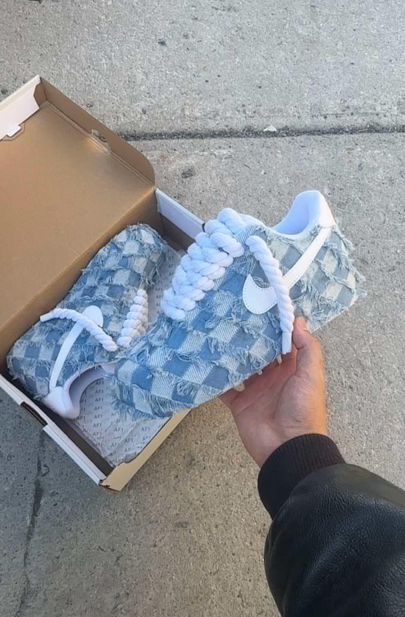 May include: A pair of light blue denim sneakers with white laces and a white Nike swoosh. The sneakers have a checkered pattern and frayed edges.