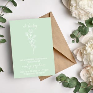 May include: A light green baby announcement card with a white floral illustration and the text "oh baby" at the top. The card announces the arrival of Ruby Sophia, born June 29, 2025 at 1:29 pm, weighing 7.5 pounds and measuring 20 inches.
