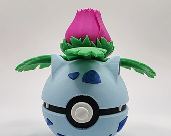 May include: A 3D-printed figure of a Pokémon character. It has a light blue body with dark blue details and a black and white circular design. A pink flower with green leaves sits on top, with two green leaves extending outwards.