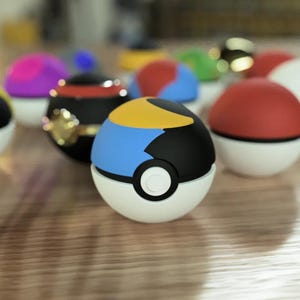 Puede incluir: Una colecci&oacute;n de Pok&eacute; Balls de colores, incluyendo una Pok&eacute; Ball azul y amarilla con un dise&ntilde;o en blanco y negro.