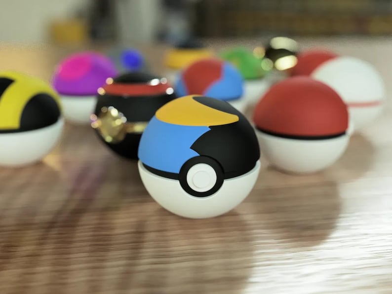 Puede incluir: Una colecci&oacute;n de Pok&eacute; Balls de colores, incluyendo una Pok&eacute; Ball azul y amarilla con un dise&ntilde;o en blanco y negro.