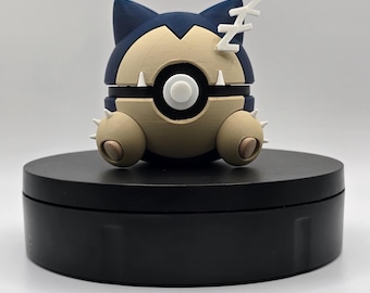 May include: A blue and brown sleeping Pokemon figurine with a white Z on its head. The figurine is on a black circular base.