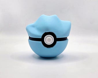 May include: A light blue, spherical object with a black band and a white circle in the center. The top of the sphere has a unique, curved shape. The object is set against a plain white background.