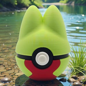 May include: A lime green and red novelty item resembling a cartoon character's head, with a black and white circular design in the center. The item is resting in water with a rocky bottom, with a natural background of trees and water.