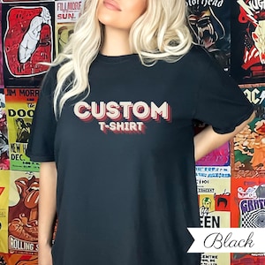 May include: Black t-shirt featuring the text "CUSTOM T-SHIRT" in a layered, retro style. The shirt is plain black. The word "Black" is written in a script font at the bottom of the image.