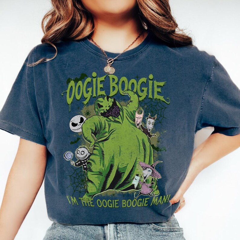 May include: A dark blue t-shirt featuring a green graphic of Oogie Boogie from The Nightmare Before Christmas. The graphic includes other characters and the text "Oogie Boogie" and "I'M THE OOGIE BOOGIE MAN!"