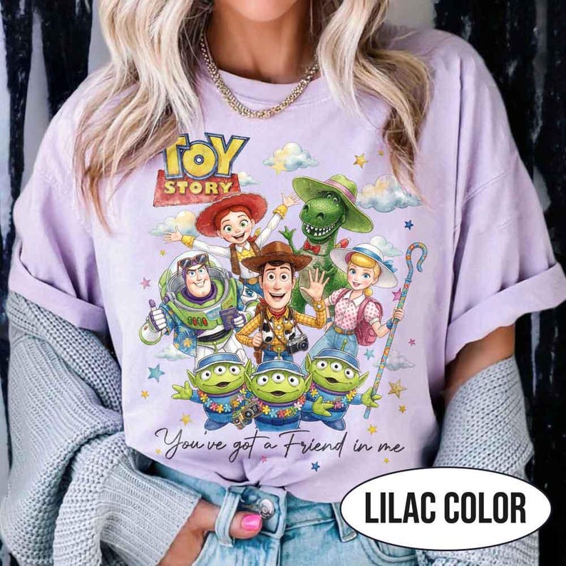 May include: Lilac-colored t-shirt featuring a graphic of characters from the animated film "Toy Story." The design includes Woody, Buzz Lightyear, and other characters, with the text "You've got a Friend in me." The shirt also has the text "LILAC COLOR."