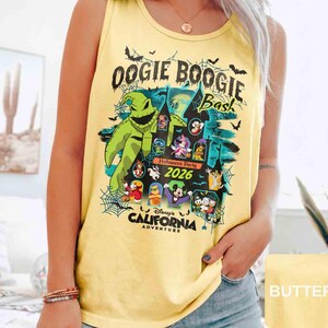 以下が含まれることがあります： ディズニー・カリフォルニア・アドベンチャーで開催されるOogie Boogie Bashハロウィーンパーティー2026のグラフィックがプリントされた黄色のタンクトップ。デザインには、ウギー・ブギーのキャラクター、お城、さまざまなディズニーキャラクターが含まれています。
