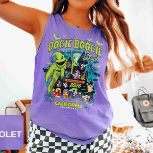 以下が含まれることがあります： 「Oogie Boogie Bash」の文字と、緑色のキャラクターやハロウィーンをテーマにしたキャラクターのグラフィックが特徴の紫色のタンクトップ。「Halloween Party 2026 California Adventure」の文字も含まれています。