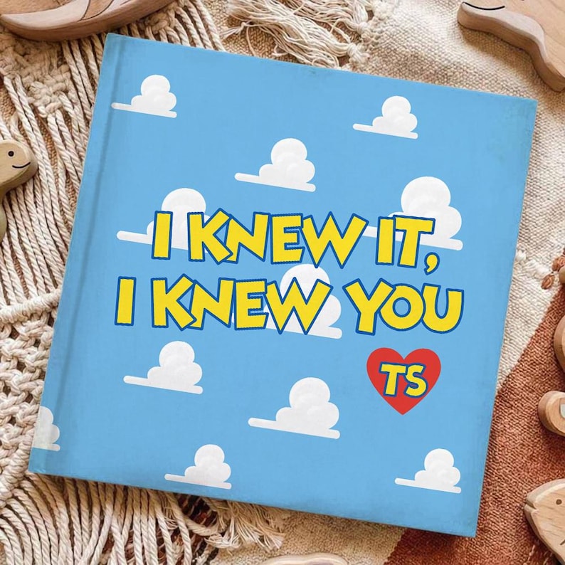 May include: A square book with a light blue cover featuring a repeating pattern of white clouds. The text I KNEW IT, I KNEW YOU is printed in bold yellow letters with a dark blue outline. A red heart icon contains the yellow letters TS.