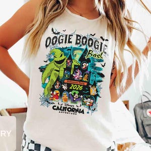 以下が含まれることがあります： 2026年のディズニー・カリフォルニア・アドベンチャーのOogie Boogie Bashのカラフルなグラフィックが特徴のアイボリー色のTシャツ。「Oogie Boogie Bash」の文字と様々なディズニーキャラクターがデザインされています。クルーネックのシャツです。