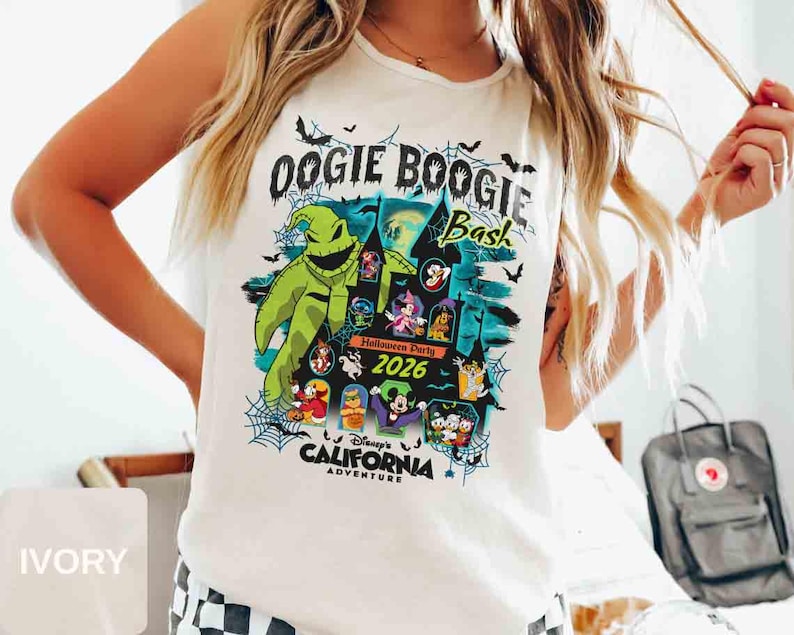 以下が含まれることがあります： 2026年のディズニー・カリフォルニア・アドベンチャーのOogie Boogie Bashのカラフルなグラフィックが特徴のアイボリー色のTシャツ。「Oogie Boogie Bash」の文字と様々なディズニーキャラクターがデザインされています。クルーネックのシャツです。