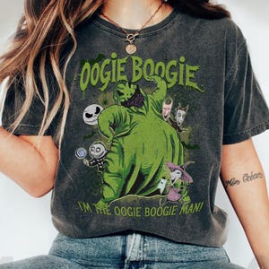 May include: Dark gray t-shirt featuring a green graphic of Oogie Boogie from The Nightmare Before Christmas, with the text "Oogie Boogie" and "I'm the Oogie Boogie Man!". The design includes other characters from the film.
